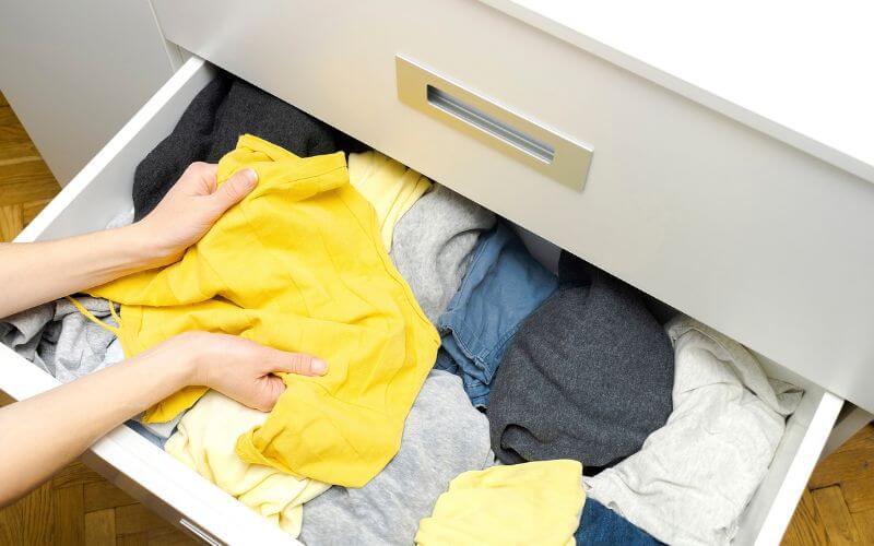 Wardrobe being decluttered with clothes sorted into keep and donate piles